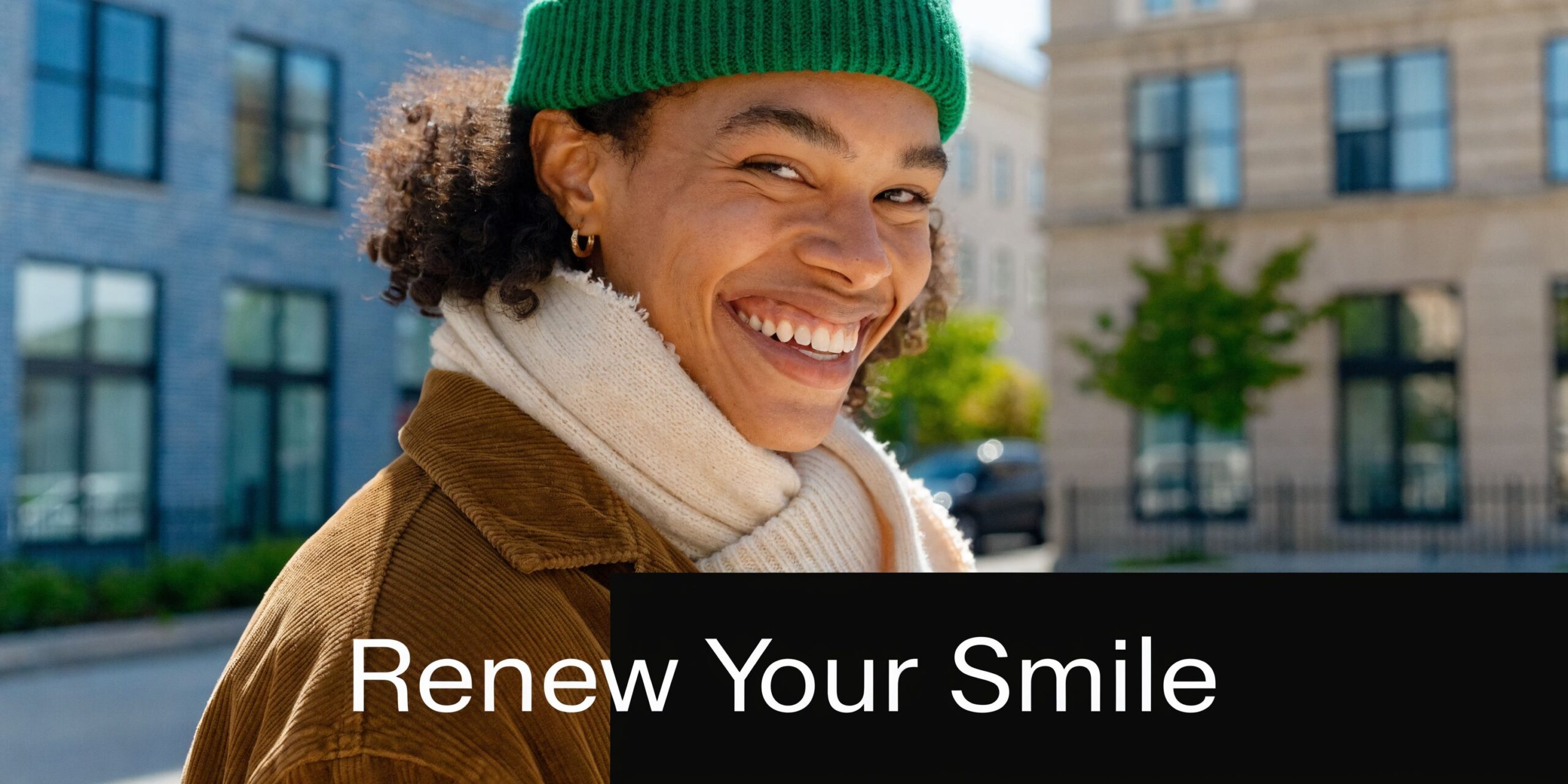 A smiling young person wearing a green beanie and brown jacket, promoting dental care services.